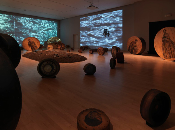 Deep River, 2013, Whitfield Lovell (American, born Bronx, NY), 56 wooden discs, found objects, soil, video projections, sound, dimensions variable. Courtesy of American Federation of Arts, the artist, and DC Moore Gallery, New York